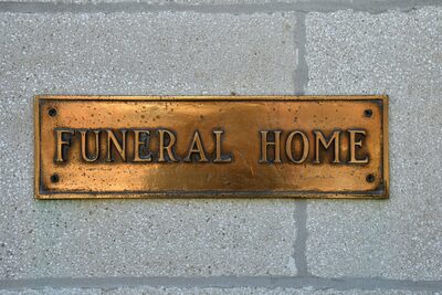 A brass funeral home sign mounted on a stone wall